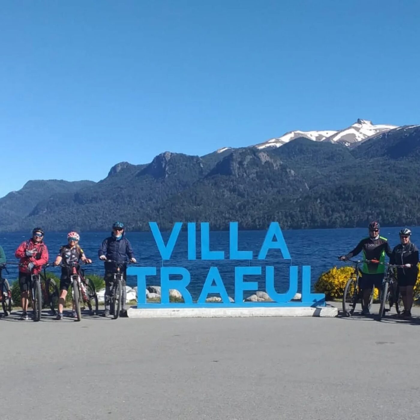 Grupo con bicicletas en cartel de Villa Traful